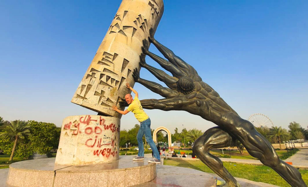 My at the Saving Iraqi Culture monument in Baghdad, pushing against 'culture' to help support it, along with a man with four arms (part of the statue).