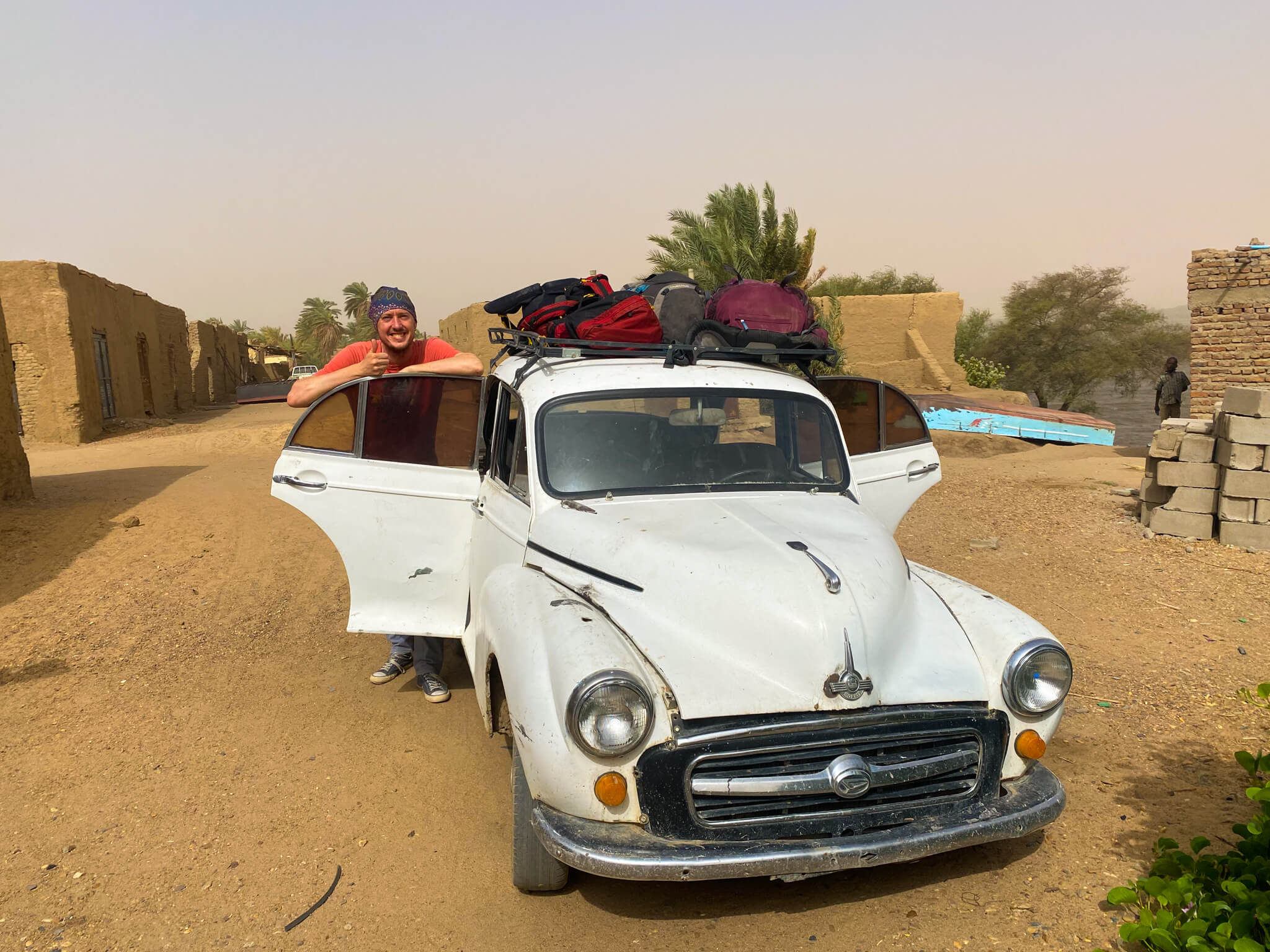 Me and our backpacks on top of a very old car in Abri.