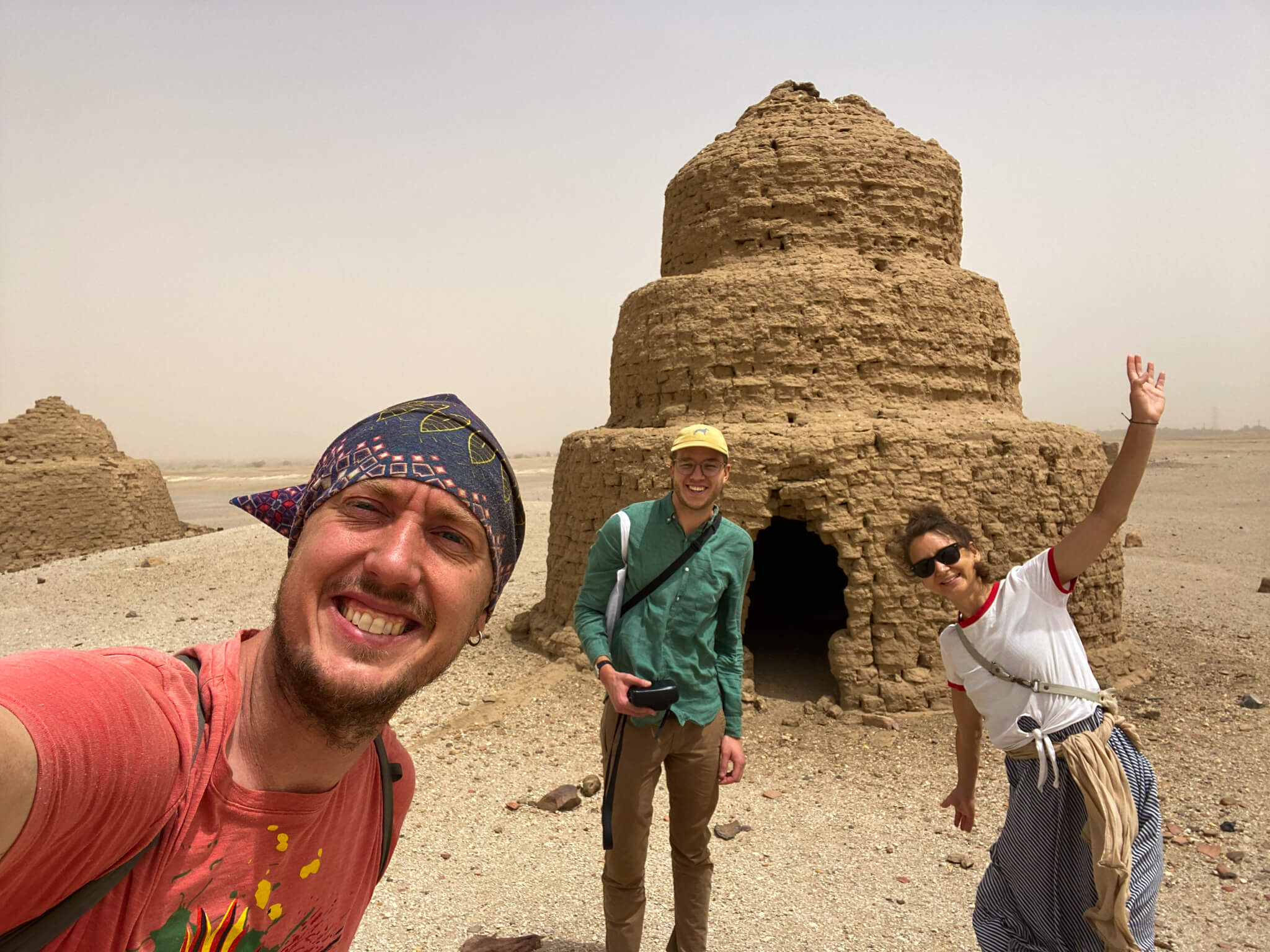 Me and two friends at an ancient stepped conical building with three layers of brick.