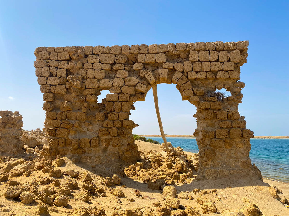 An crumbling coral archway with the sea in the background.