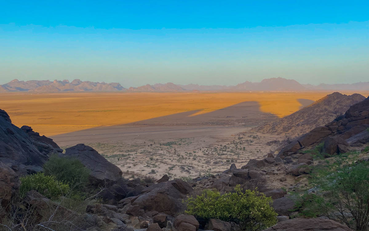 The view over the flat plains between the Taka Mountains and the border with Eritrea. The mountains cast a shadow over the orange plain.