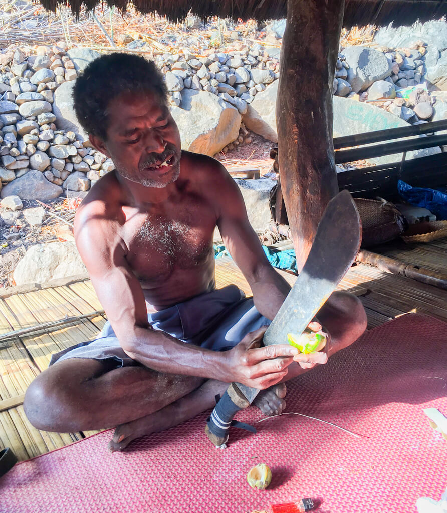 The tribal chief cutting betel nut with a machete