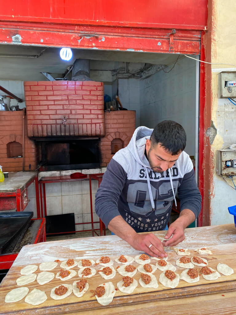 A local man makes sfeeha in front of a brick oven