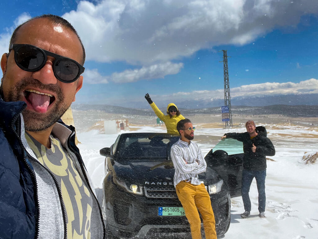 The four of us posing by our convertible with the roof down in the snow