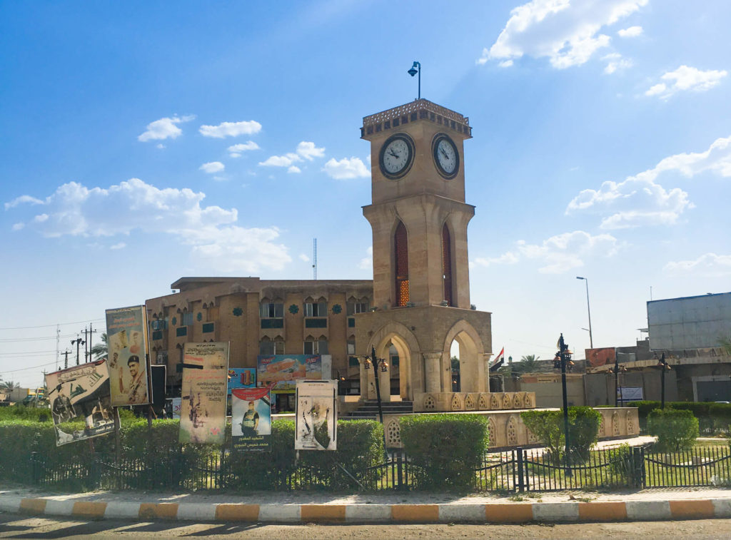 A square with a clock tower and Arabic signs around it.