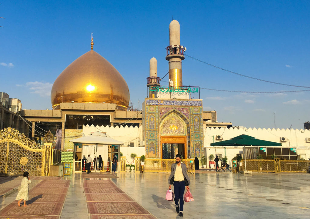 The front of the mosque with carpets on the ground and its beautiful golden dome glistening in the sunshine.