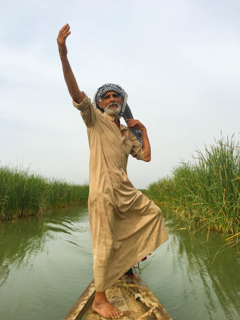 Our boatman standing in the boat and waving his arms in the air.