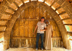Me and a Madan man with arms locked together in a hut made of reeds.