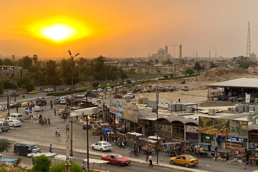 A market in Mosul at sunset with the Mosul Grand Mosque in the background.