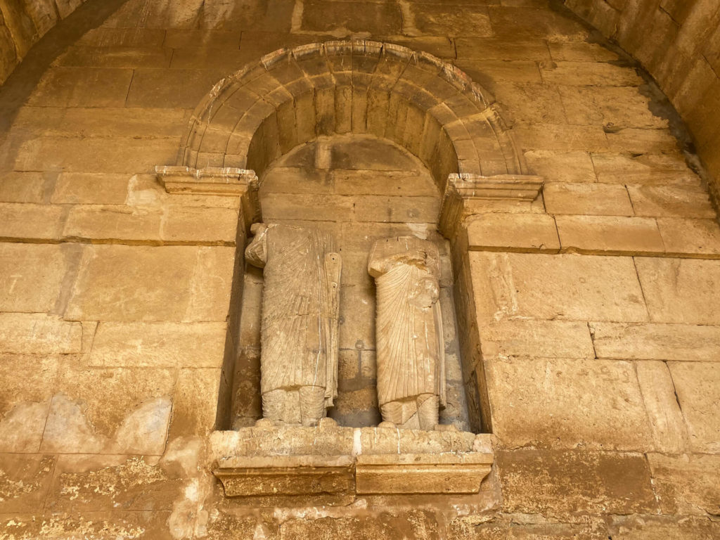 Two beheaded statues in an alcove.