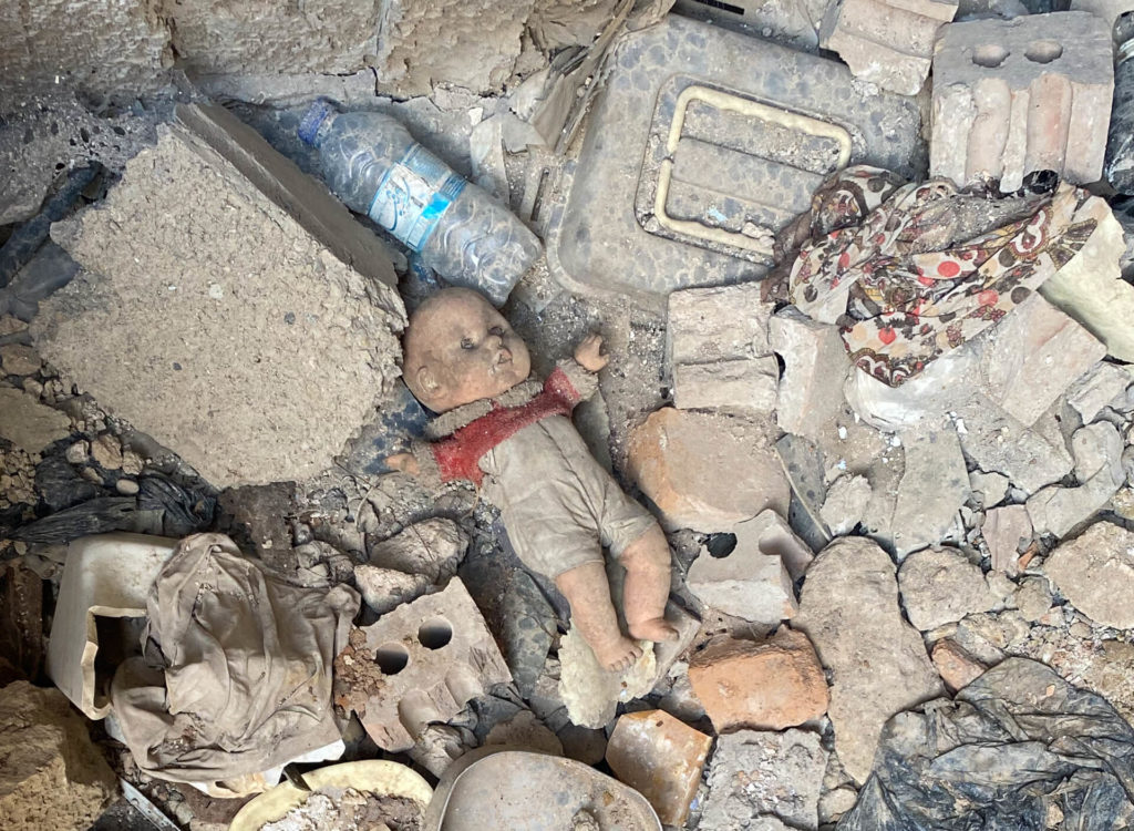 A doll lying among rubble.