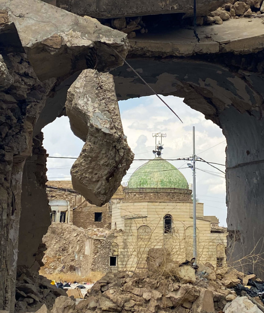 The green dome of the Umayyad Mosque seen through a hole in the wall of a building in the old town of Mosul.