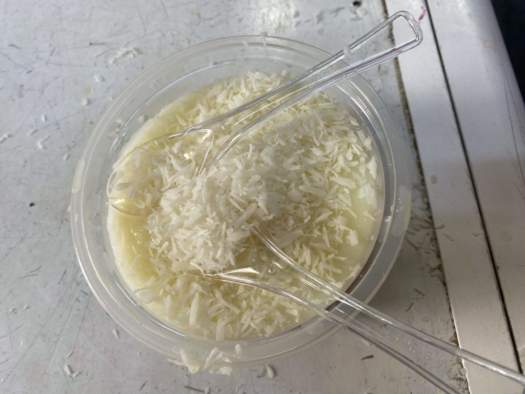 Rice pudding with grated coconut in a plastic dish.