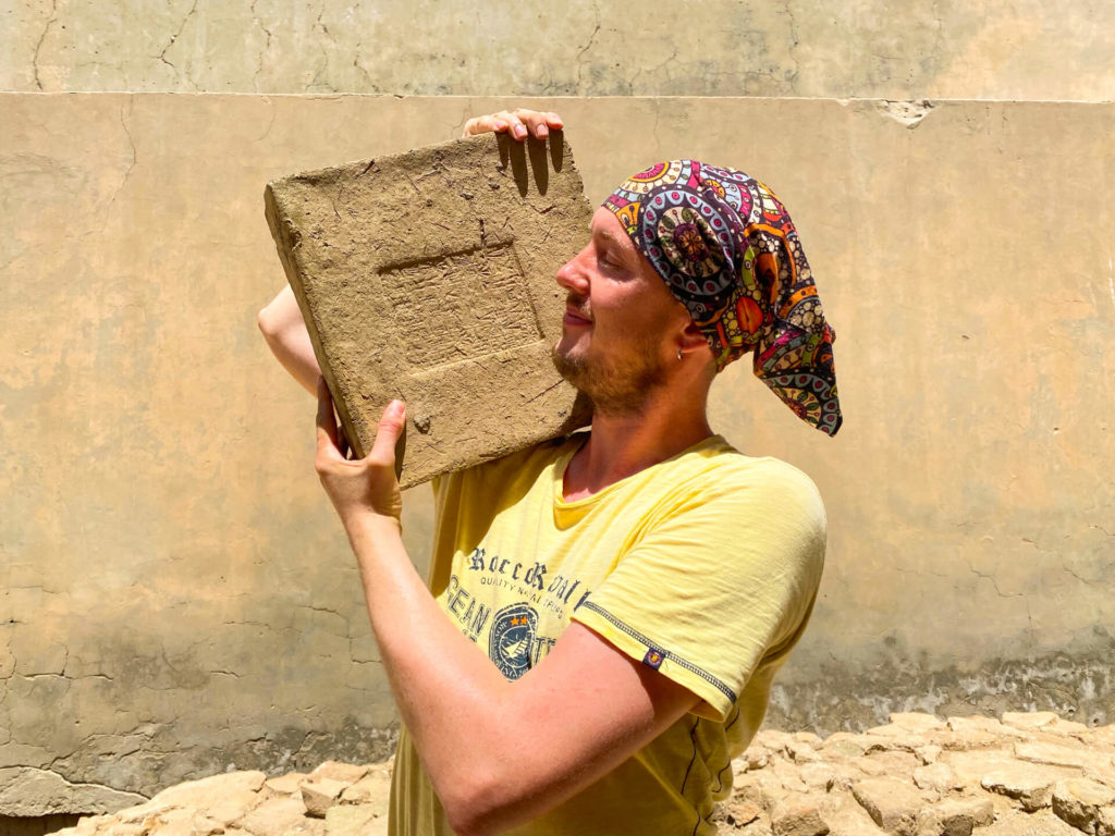 Me, hold a brick with ancient writing on it on my shoulder.