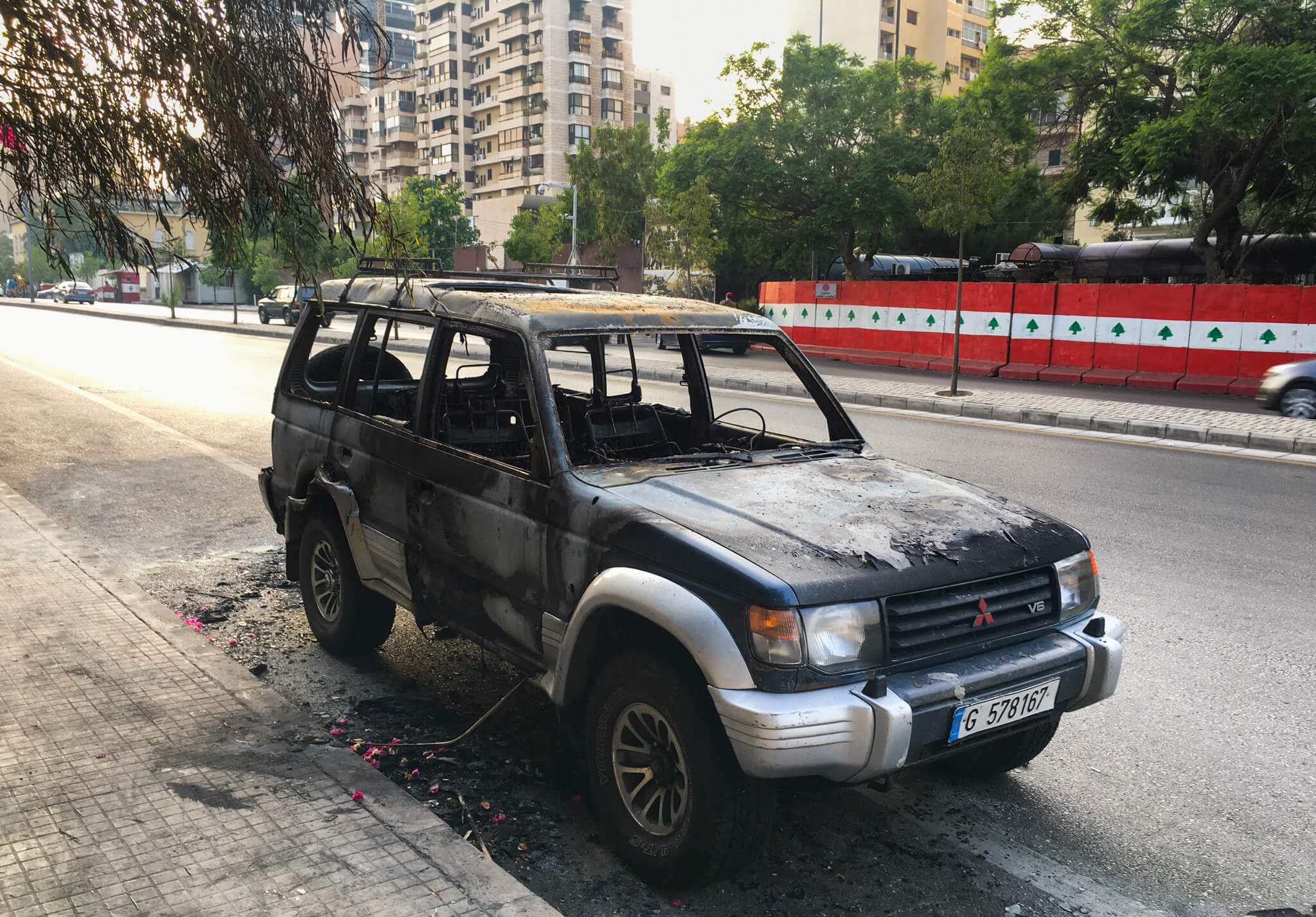 A burned out car on the edge of a road in Beirut.