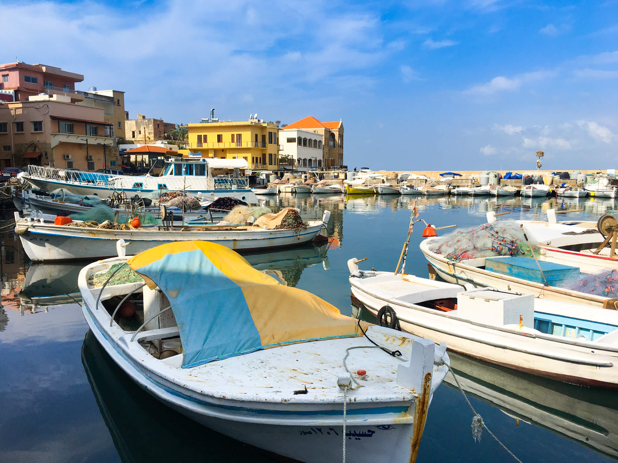 A harbour full of little fishing boats with colourful buildings in the background.