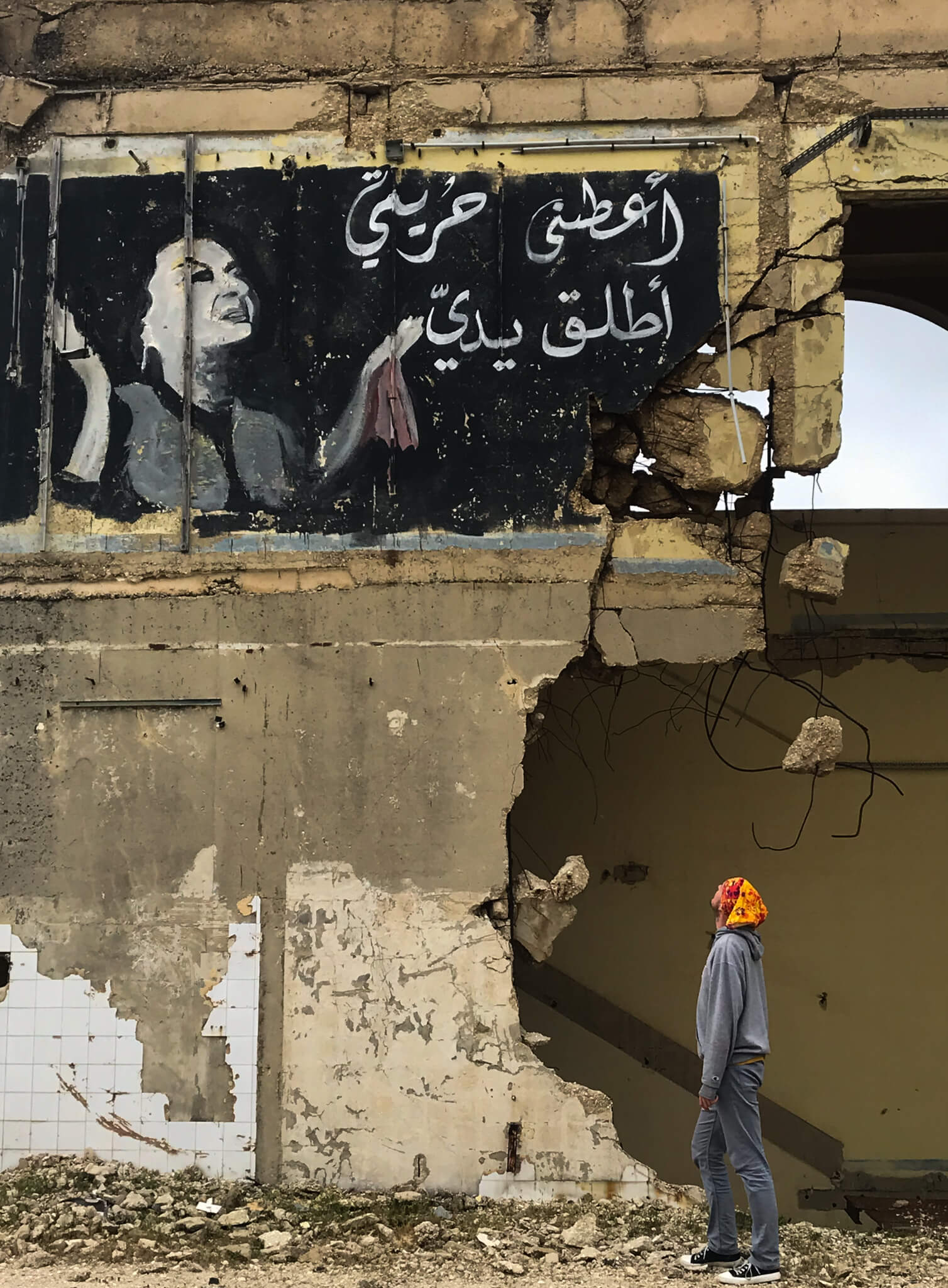 An badly-damaged building with graffiti of a famous Egyptian singer with her Lyrics written in Arabic.  