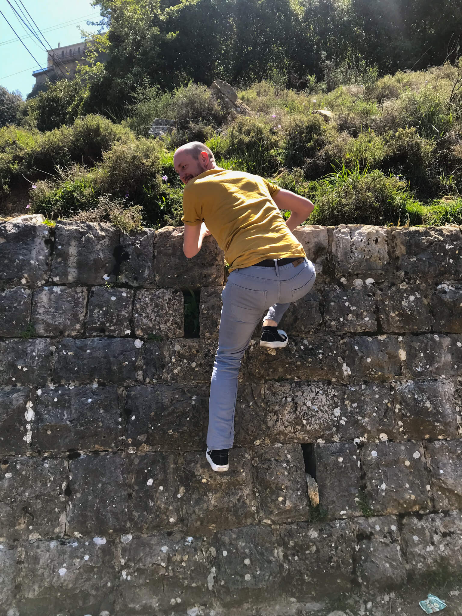 Me, climbing over a brick wall