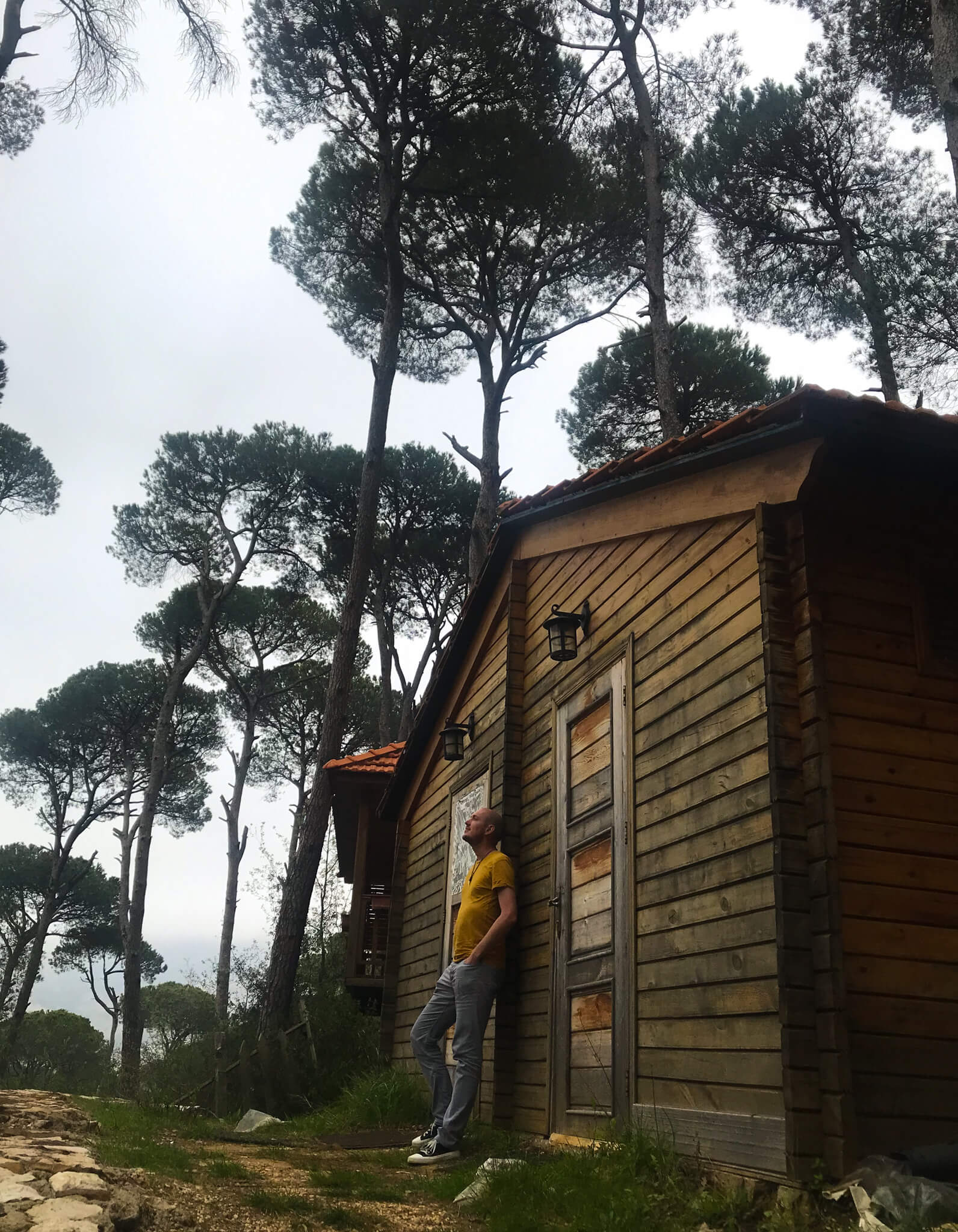 Me standing against the door of a wooden cabin surrounded by pine trees