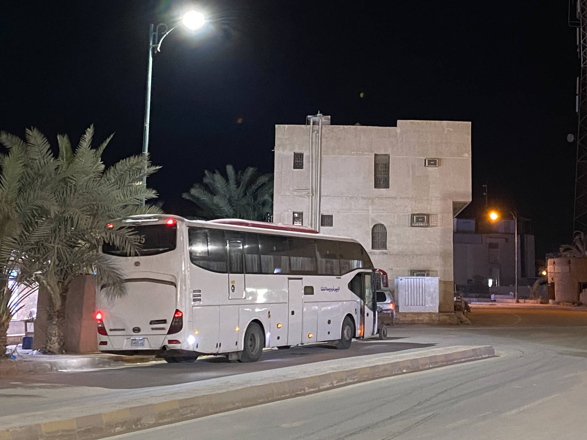 A modern bus parked on a street at night.
