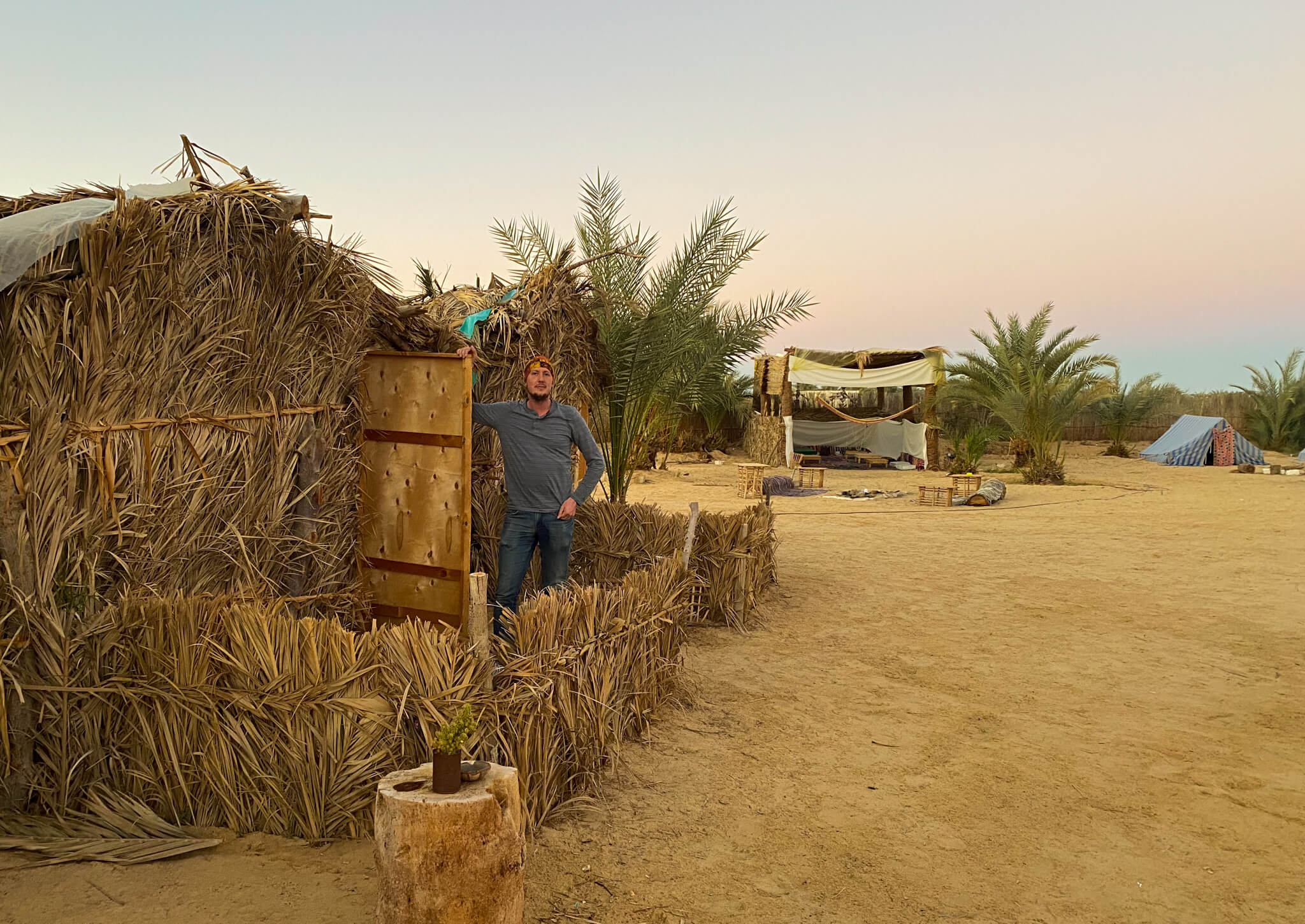 Me standing at the entrance of a hut made out of dried grass.