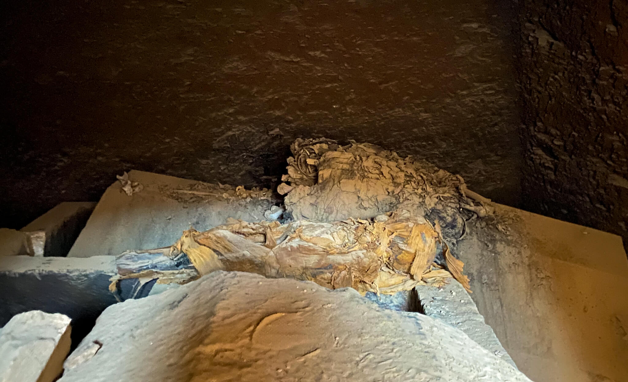 A small mummy inside an open tomb.