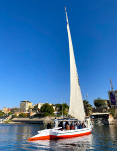 A felucca boat on the Nile with Aswan city in the background.
