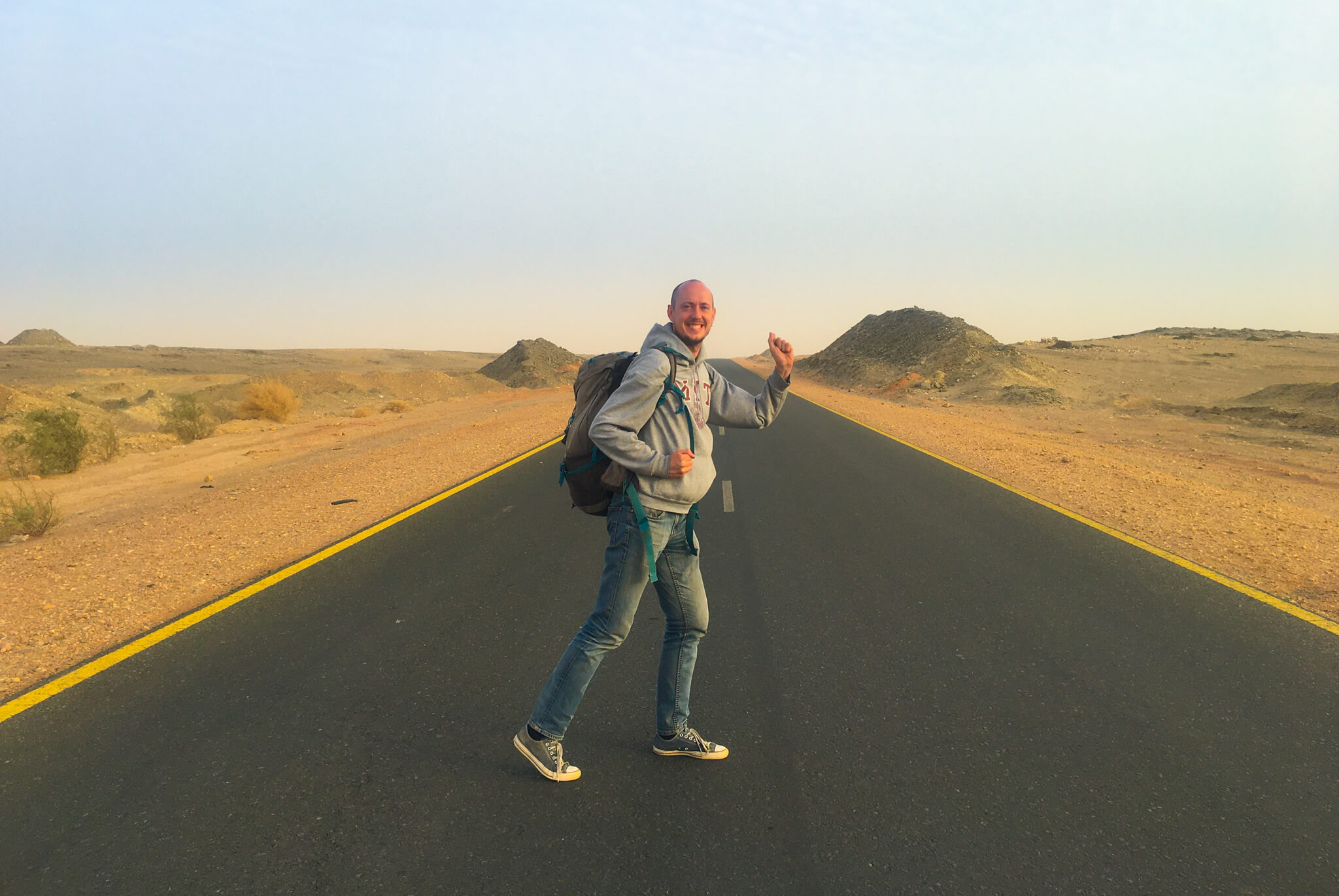 Me, standing on a highway in the Sahara desert, about to walk into the sand