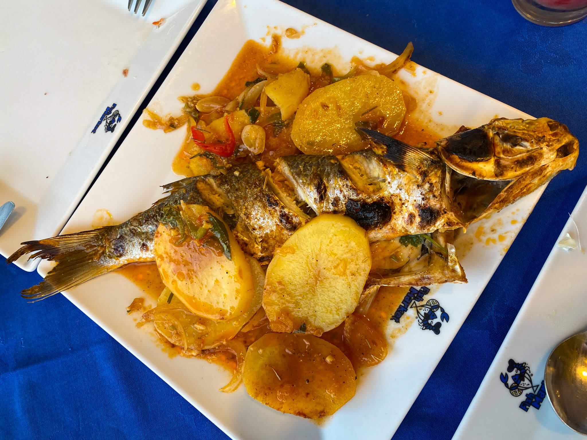 A big plate of fish in a sauce with potatoes.