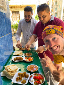 Me, eating foul and falafel for breakfast, while standing outside with two local guys.