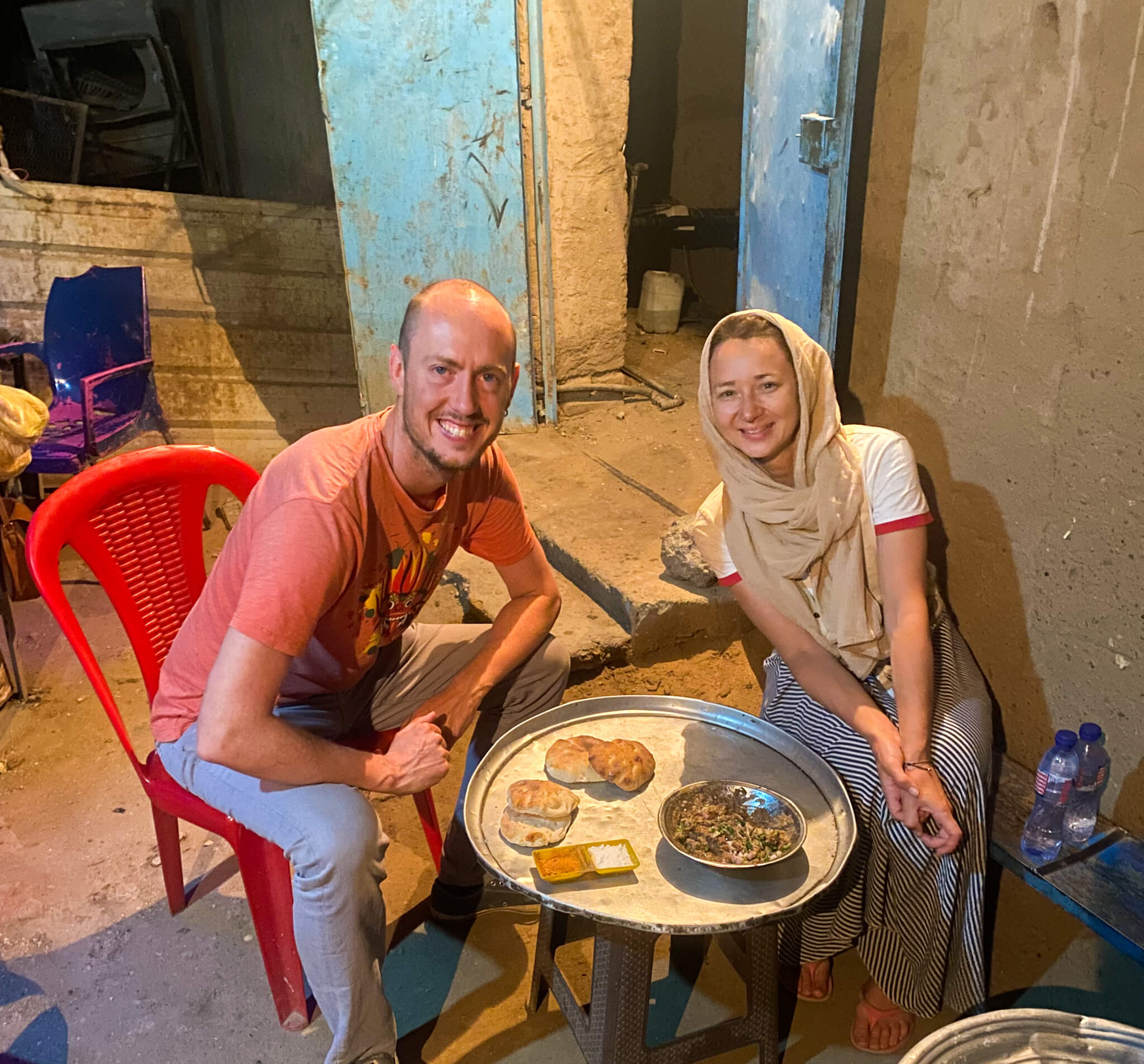 Me and Anna eating foul on a wooden table and plastic chairs on the edge of the street.