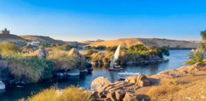 The River Nile with a felucca and sand dunes in the background. On the left is the Mausoleum of Aga Khan