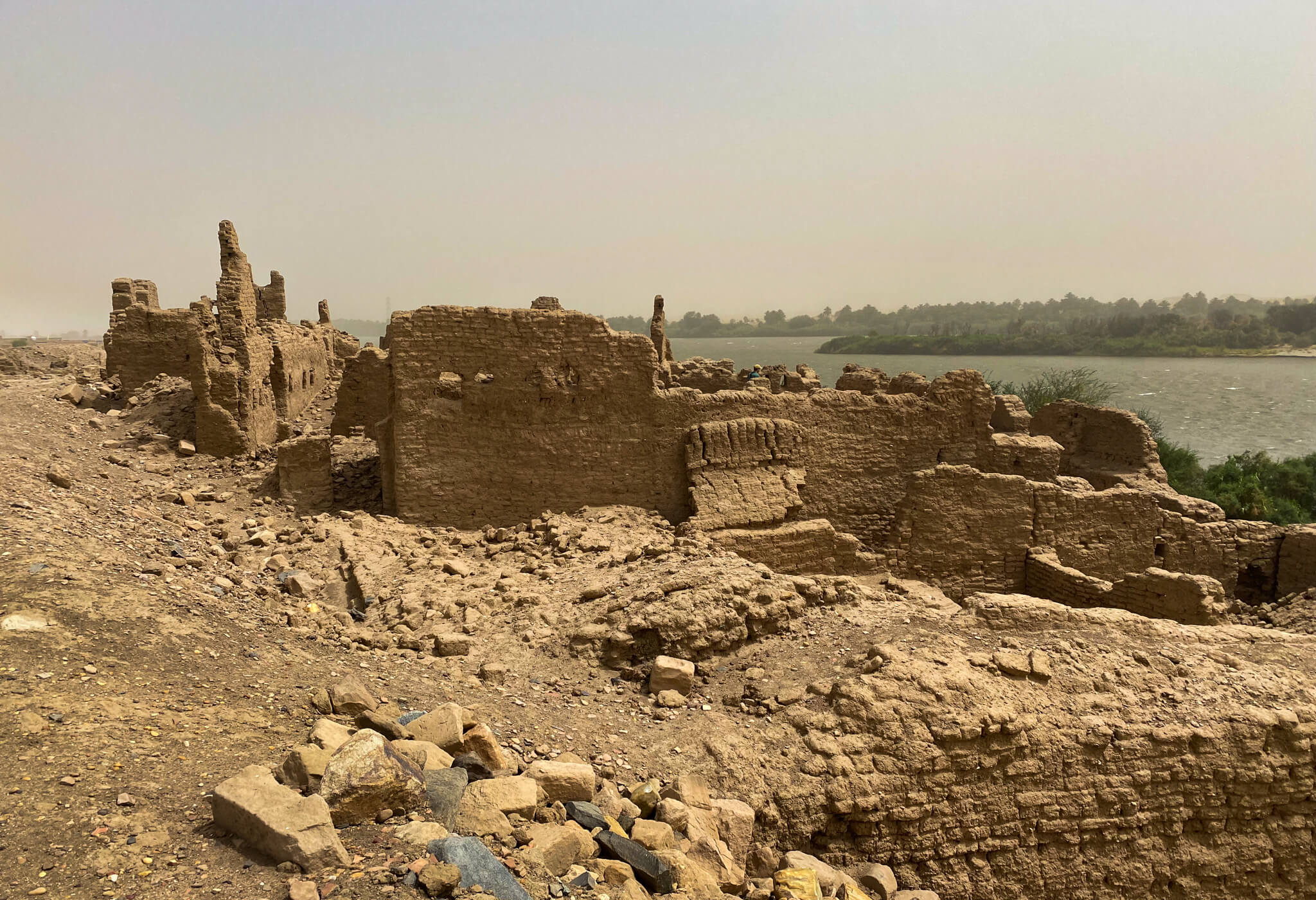 Some crumbling walls of an ancient building with the Nile in the background.