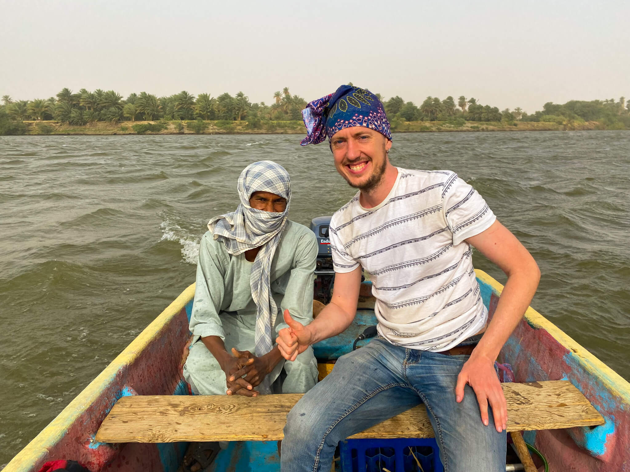 Me in a small motorboat crossing the Nile.  My boatman sits in the back wearing traditional Nubian clothes.