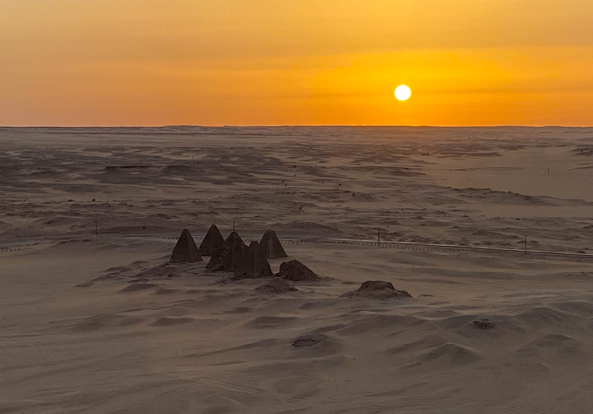 The sun setting in the distance over the Barkal Pyramids.