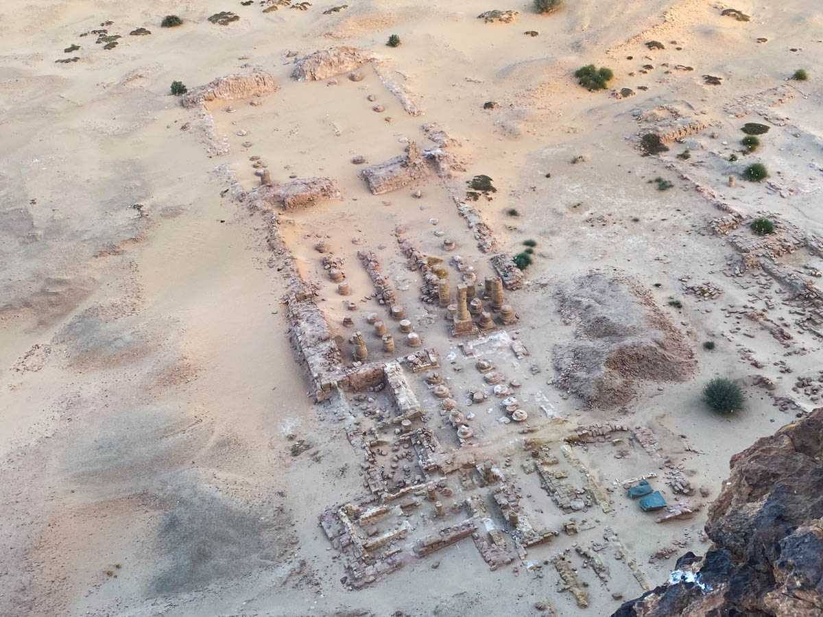 An aerial view of the Temple of Amun showing its vast size marked by pillars in the desert below. 