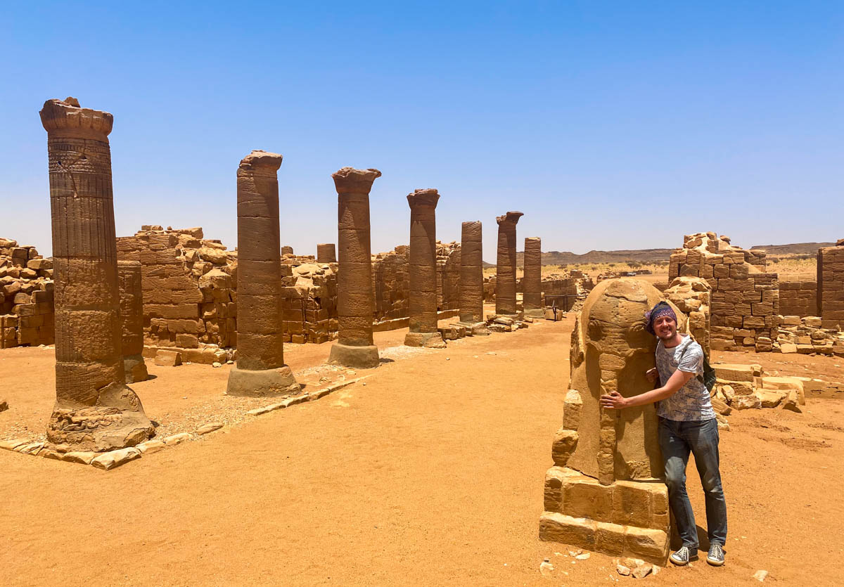 Me holding an elephant statue with a row of pillars in the background.