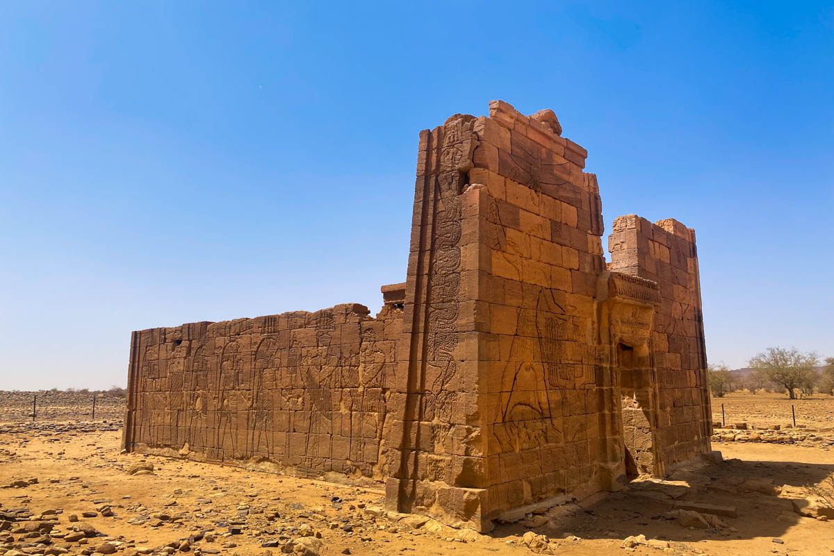 An ornately carved temple standing in the desert.