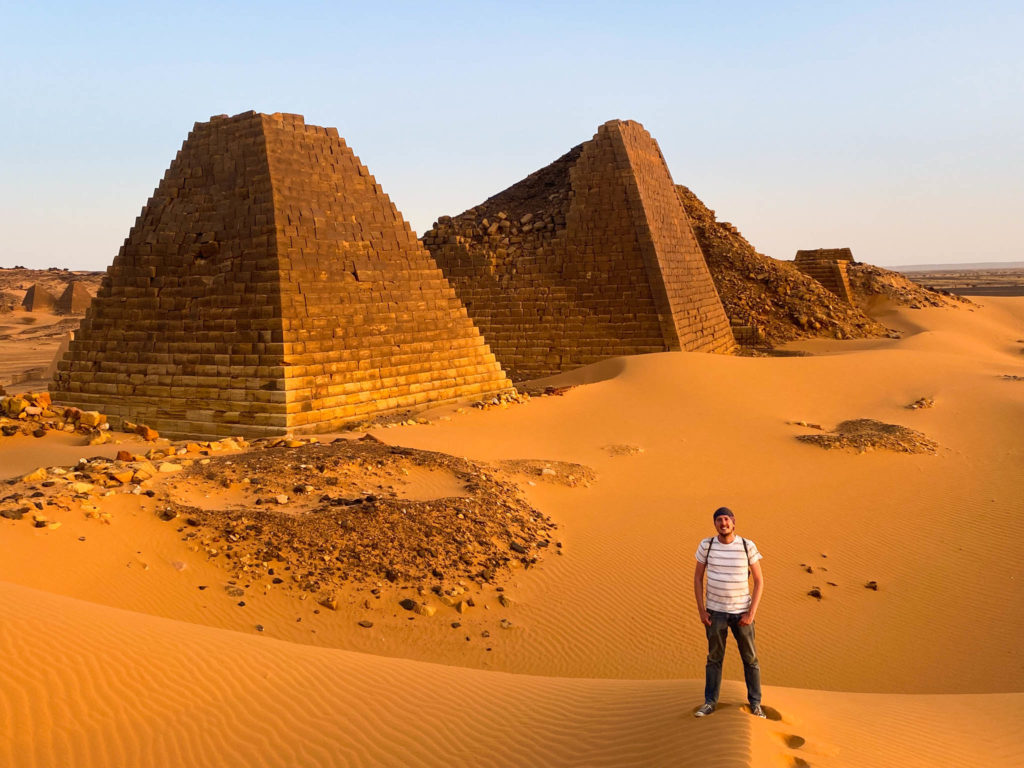 Me, standing a distance in front of two of the Pyramids of Meroe with the golden sands rolling away behind me.