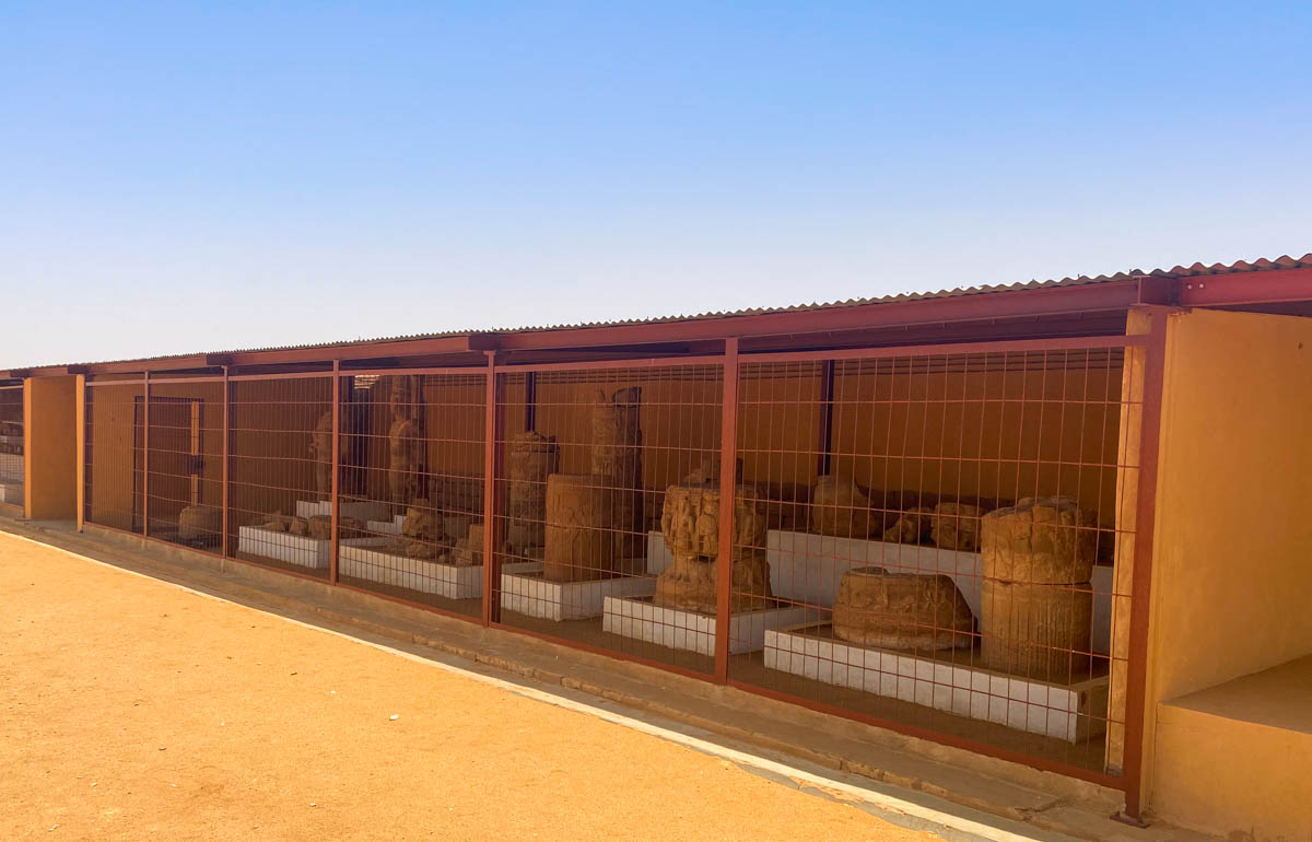 A shed containing a collection of statues with a metal mesh at the front to stop people entering.