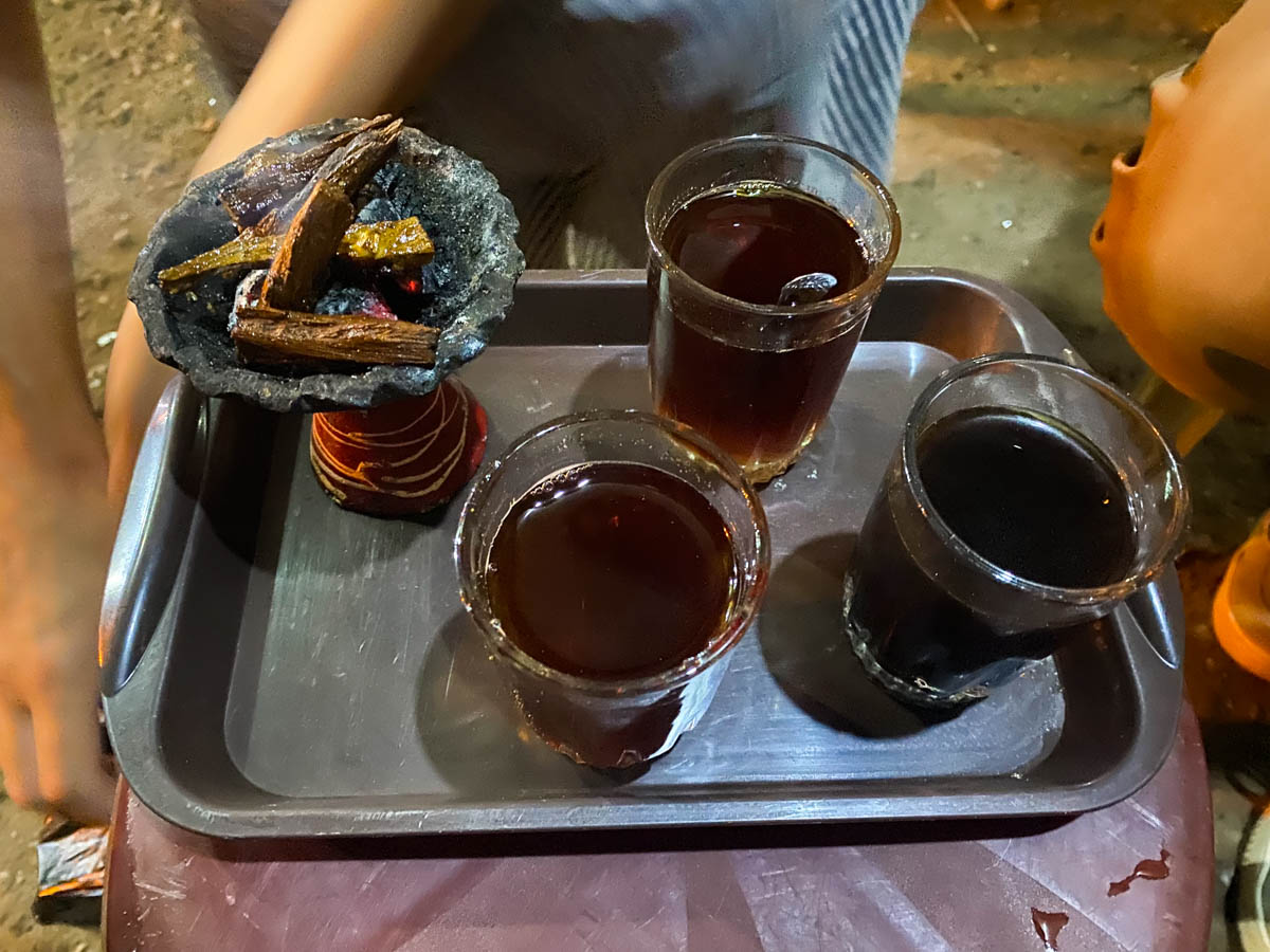 3 cups of tea on a metal tray with a bowl of incense next to it.