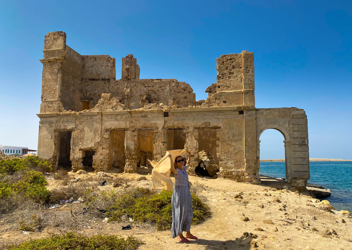 Anna standing in front of a partially collapsed two-storey building.