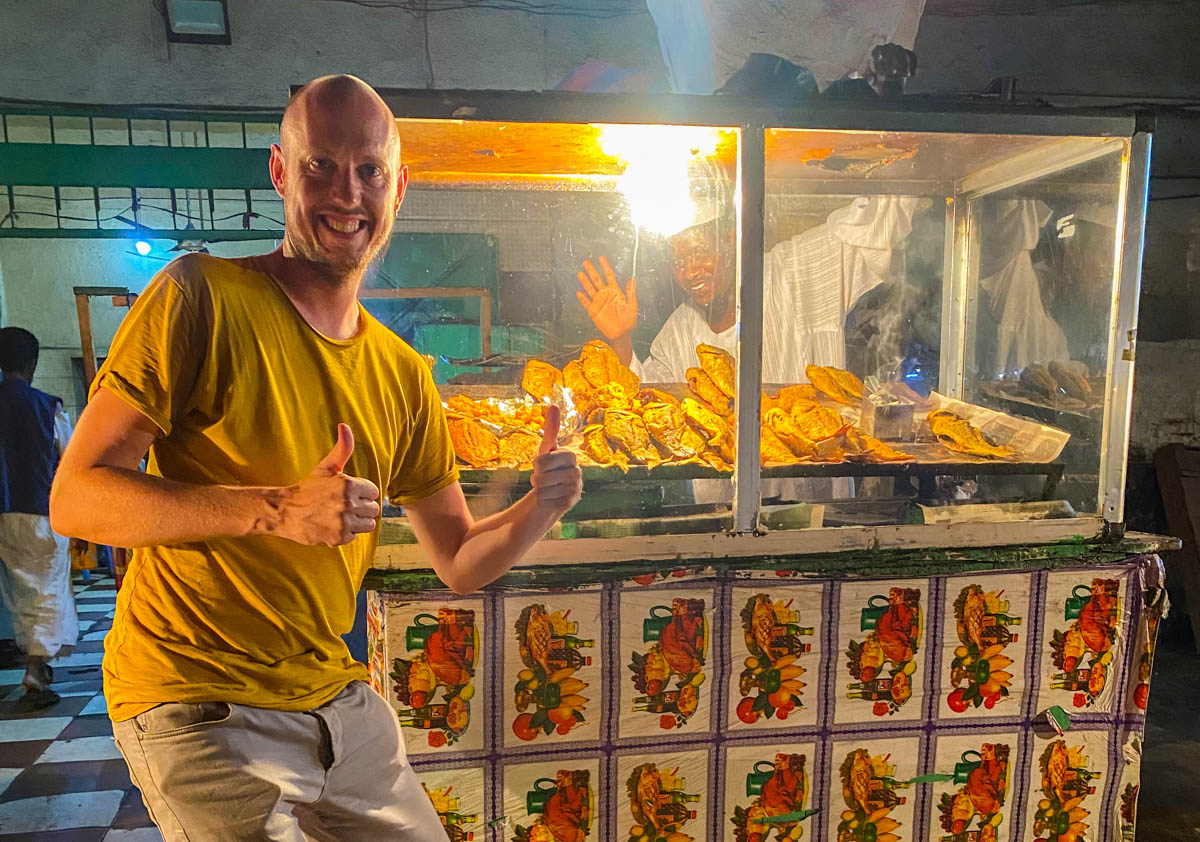 Me, giving a thumbs up, in front of a street food fried fish vendor