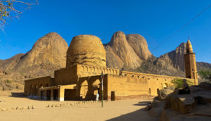 Men praying outside the Khatmiyah Mosque with the Taka Mountains rising in the backgrounds.