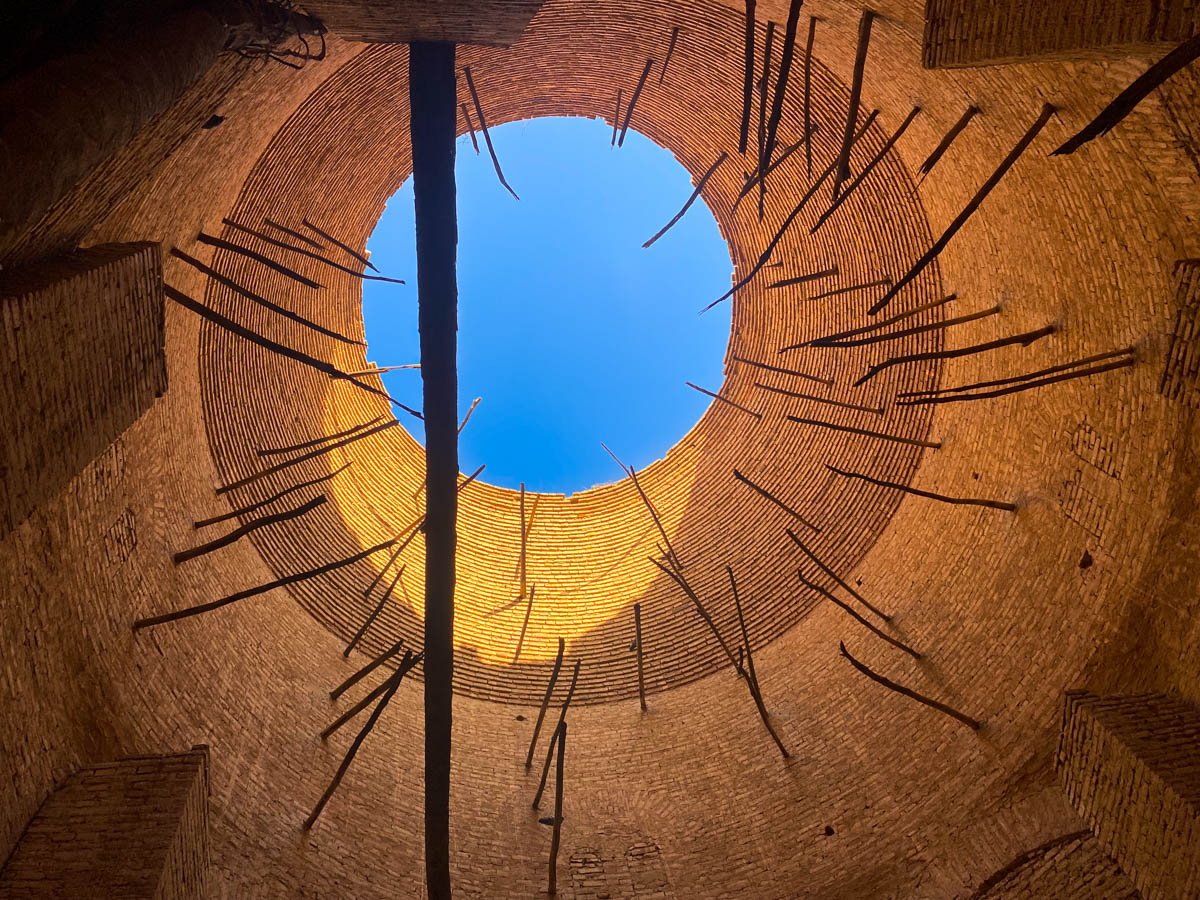 Looking up at a circular dome with blue sky visible through a hole in the centre