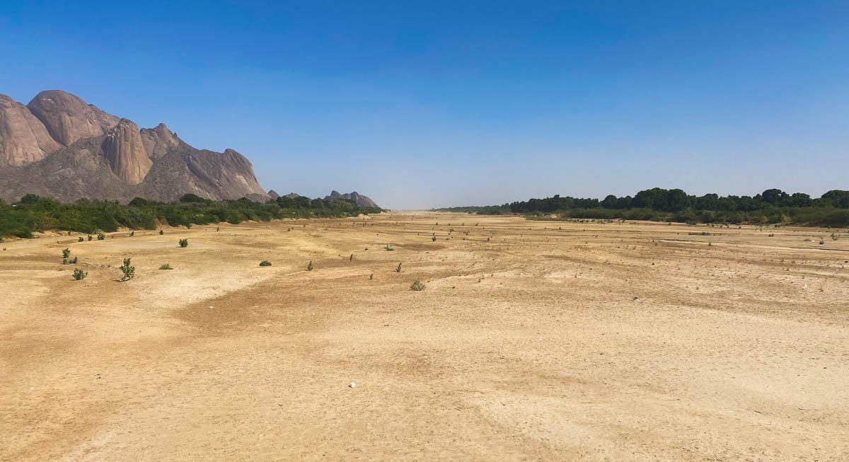 The dry sandy riverbed spreads out in the distance with part of the Taka Mountains visible on the left.