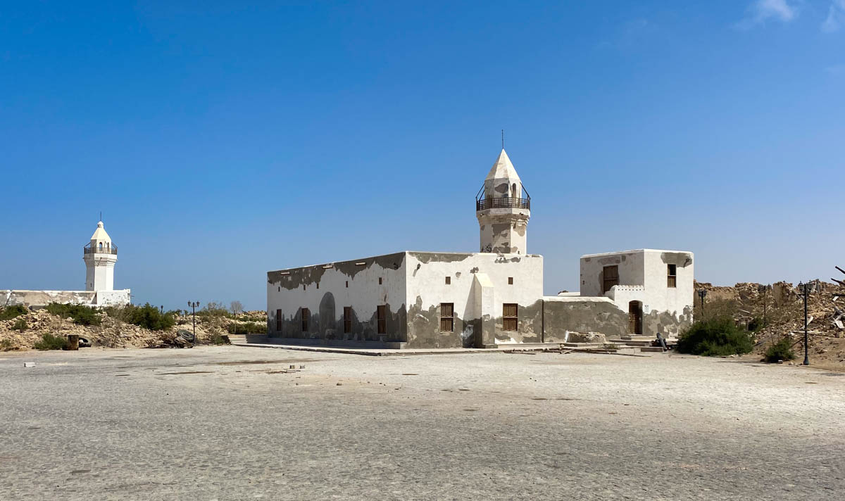 A building with peeling white paint on Suakin Island with a short tower.