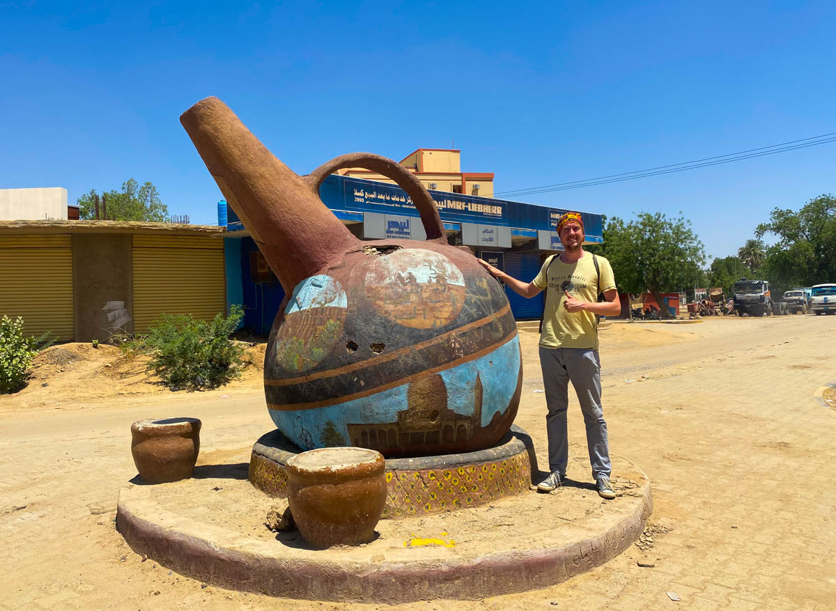 Me standing beside a giant statue of a traditional Sudanese coffee pot.