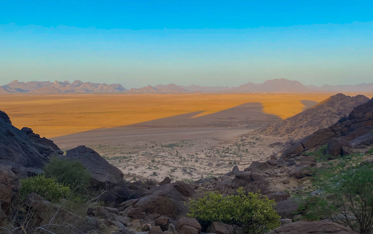 The view over the flat plains between the Taka Mountains and the border with Eritrea.  The mountains cast a shadow over the orange plain. 